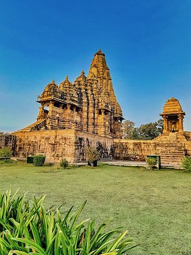 Fotografía del templo hindú Kandariya Mahadev con hierba y vegetación delante