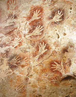 Varias huellas de manos en la pared de una cueva.
