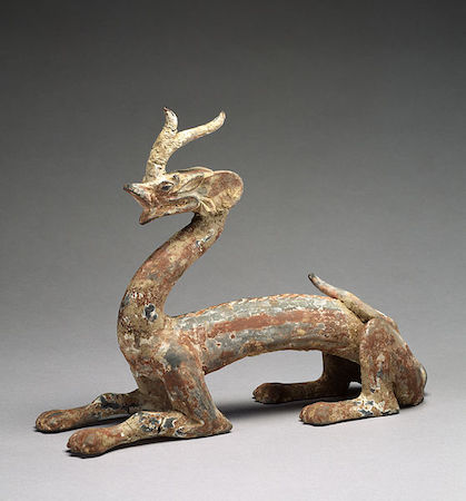 Una escultura de cerámica de una criatura parecida a una serpiente con patas de mamífero y un solo cuerno.