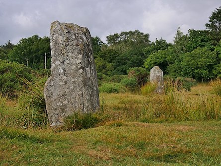 Fotografía de dos grandes piedras verticales en un campo, que son menhires megalíticos