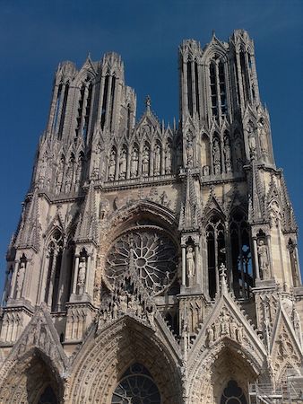 Una fotografía de la fachada frontal de la catedral de Reims, que muestra sus dos torres y su rosetón.