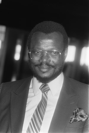 Una fotografía en blanco y negro del príncipe Mangosuthu Buthelezi, un hombre africano, con gafas grandes y traje.