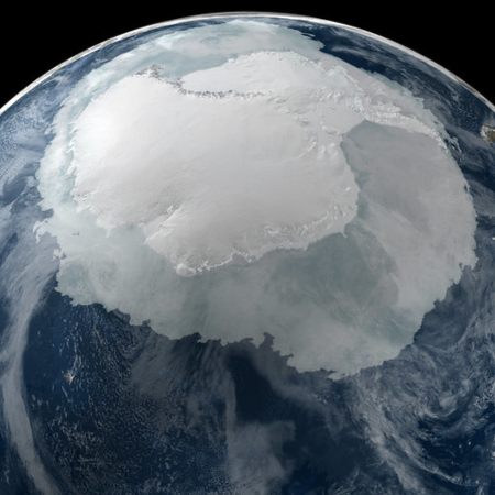 Un continente blanco, una capa de hielo gris, agua de un azul profundo y nubes blancas se ven cuando se ve la Antártida desde el espacio.