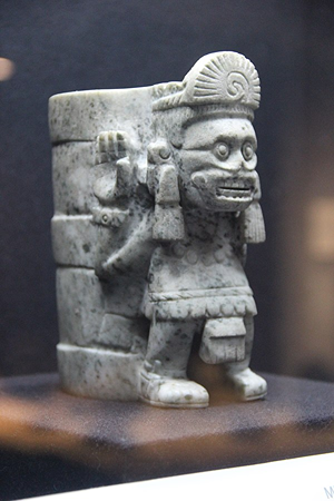 Imagen de un vaso azteca de piedra gris que muestra a Mictlantecuhtli con ojos grandes y dientes descubiertos