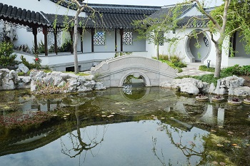 Puente con apertura semicircular reflejada en jardín piscina
