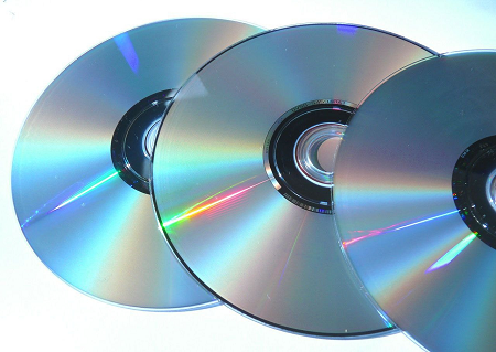 La imagen muestra varios patrones en forma de arcoíris en las superficies de tres CD.
