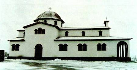 Una fotografía de una iglesia blanca con detalles negros y un techo abovedado.