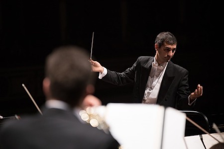 Foto de un director frente a una orquesta.