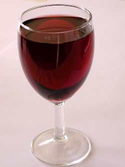 Una imagen de una copa de vino llena de vino tinto en un restaurante.