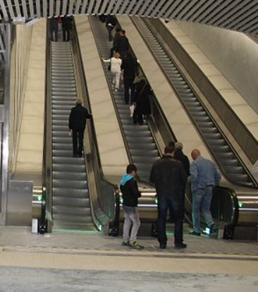 Las personas en un centro comercial suben a una escalera mecánica.