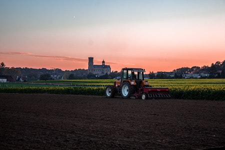 Fotografía en color de un tractor moviéndose cerca de un campo.