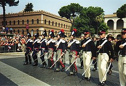 Imagen en color de oficiales en distintos ejemplos del uniforme de Carabinieri, algunos llevan el sombrero de plumas del uniforme de gala