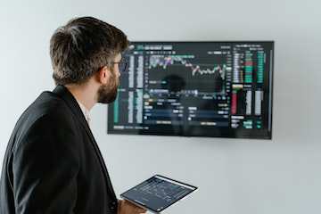 Una foto de un chico mirando una pantalla en la pared que muestra el mercado.