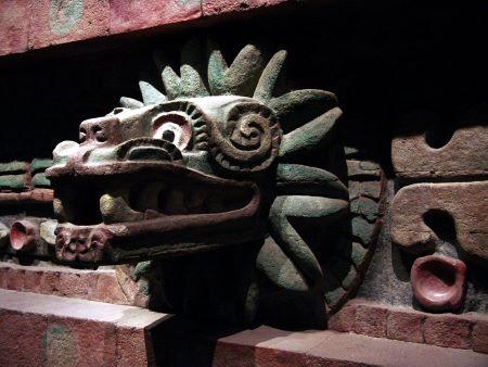 Una talla en piedra de la serpiente emplumada, con plumas azules visibles alrededor de su cabeza, al estilo de la antigua talla azteca.