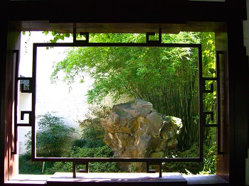 Vista de rocas y plantas a través de la ventana en el jardín chino