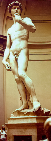 Una estatua de David de mármol blanco y desnuda cambia su peso sobre una pierna y lleva la mano opuesta hacia el pecho.