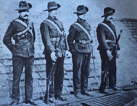 Cuatro hombres armados y uniformados se encuentran en formación en una azotea