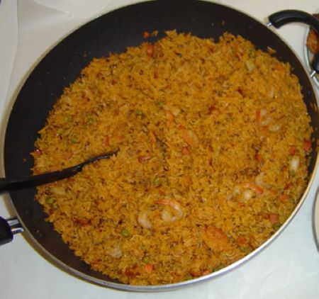 Una sartén grande con arroz rojo anaranjado y camarones.