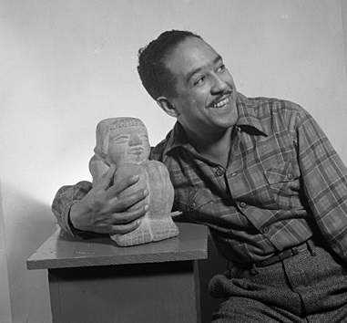 Imagen de un hombre alegre sosteniendo una estatua y sonriendo.