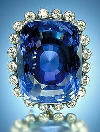 La imagen muestra un gran zafiro azul rodeado de pequeños diamantes.