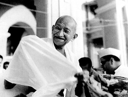 Fotografía en blanco y negro de Mahatma Gandhi en un podio con micrófono
