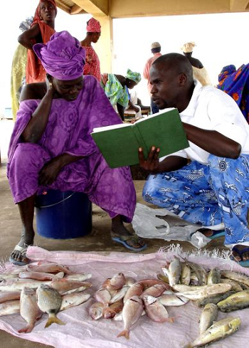 Un hombre leyendo un libro a una mujer.