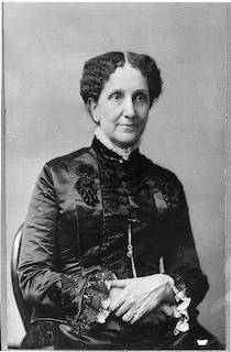 Un retrato de Mary Baker Eddy, sentada en una silla con las manos cruzadas en el regazo y vestida con un vestido victoriano negro.
