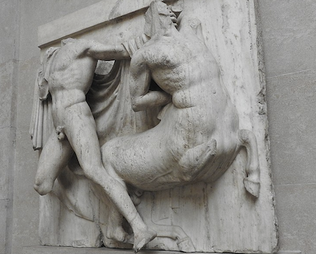 Una talla de mármol en alto relieve de un hombre luchando contra un centauro, vista de perfil. Las figuras están dañadas, les faltan cabezas y extremidades.