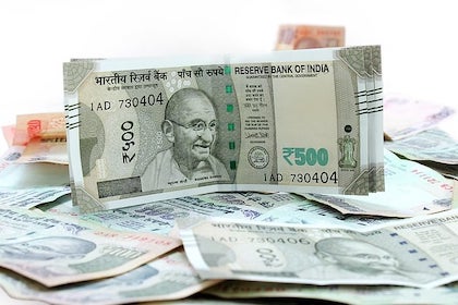 Fotografía de billetes de rupias indias sobre una superficie blanca.