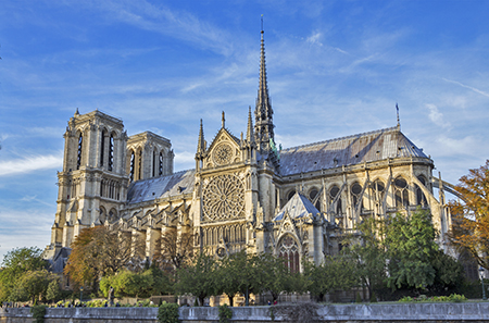 Una vista lateral de Notre Dame muestra un gran rosetón, una aguja, dos torres y arbotantes.