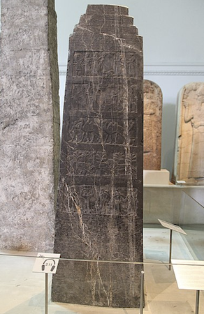 Un gran obelisco negro expuesto entre otros monumentos en la galería de un museo