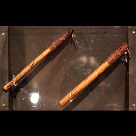 Exhibición de dos bolígrafos para tatuajes que son herramientas de madera en forma de martillo con un peine para perforar la piel en el extremo.