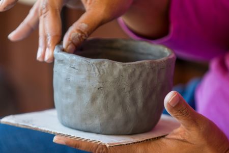 un alfarero hace una vasija pequeña pellizcando arcilla en forma de cuenco
