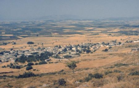 Pequeño pueblo rodeado de campos de cultivo y colinas.