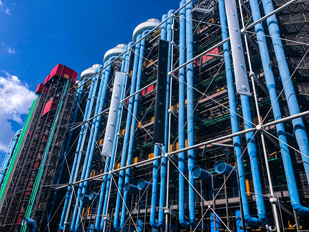 Exterior del edificio que muestra tuberías azules y elementos de diseño verdes y rojos.