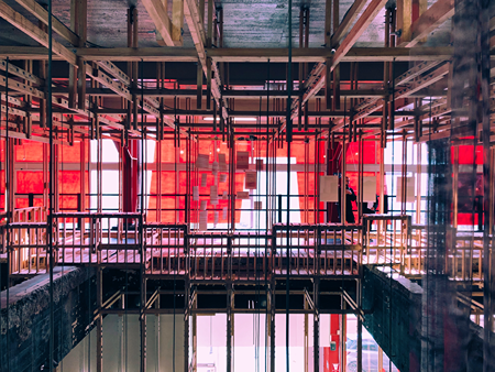 Diseño interior detallado del edificio con sistemas de soporte expuestos y ventanas de vidrio.