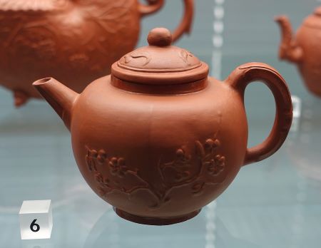 una pequeña tetera hecha con arcilla roja y grabada con un diseño floral