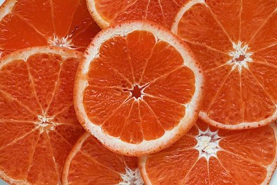 Una imagen de rodajas de naranja cortadas transversalmente, de modo que los segmentos del carpelo sean visibles.