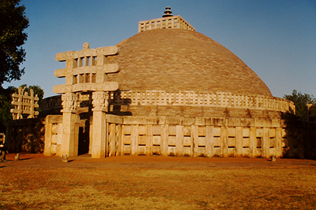 Una gran estructura de piedra con una parte superior abovedada y una puerta escultórica de piedra tallada en el frente.