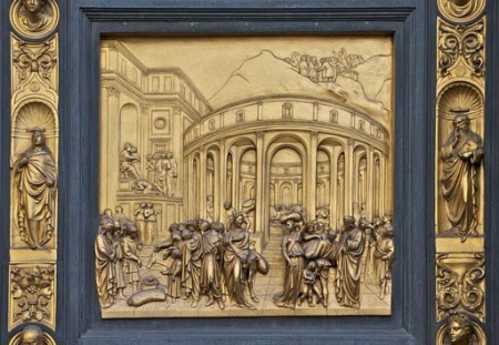 Un panel de historia de bronce dorado intrincadamente detallado rodeado de esculturas.