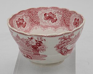 Taza de té sin asa. Fondo blanco con diseños florales y pastorales de color rosa.