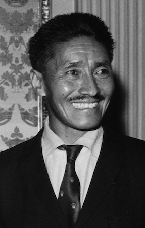 Una fotografía en blanco y negro de Tenzing Norgay, vestido con traje y sonriendo.