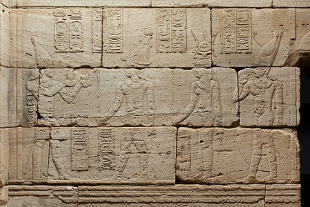 Porción de un muro de piedra del templo con tallas de cuatro dioses egipcios y jeroglíficos