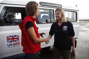 Dos trabajadores de UKAID junto a un camión