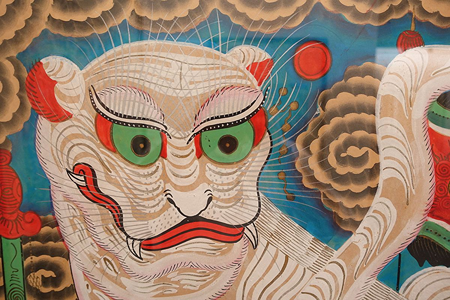 Imagen de un tigre con ojos verdes, labios rojos y fondo rojo y azul.