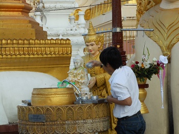 Un joven lava ritualmente una estatua del bebé Buda.