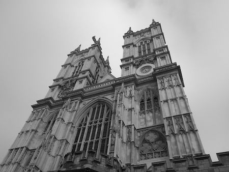 Una fotografía en blanco y negro de la fachada de la Abadía de Westminster, una iglesia con grandes ventanales y un exterior decorativo.