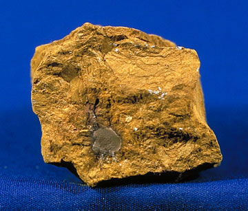 Un pequeño trozo de ocre amarillo, casi mostaza, sobre un fondo vacío.